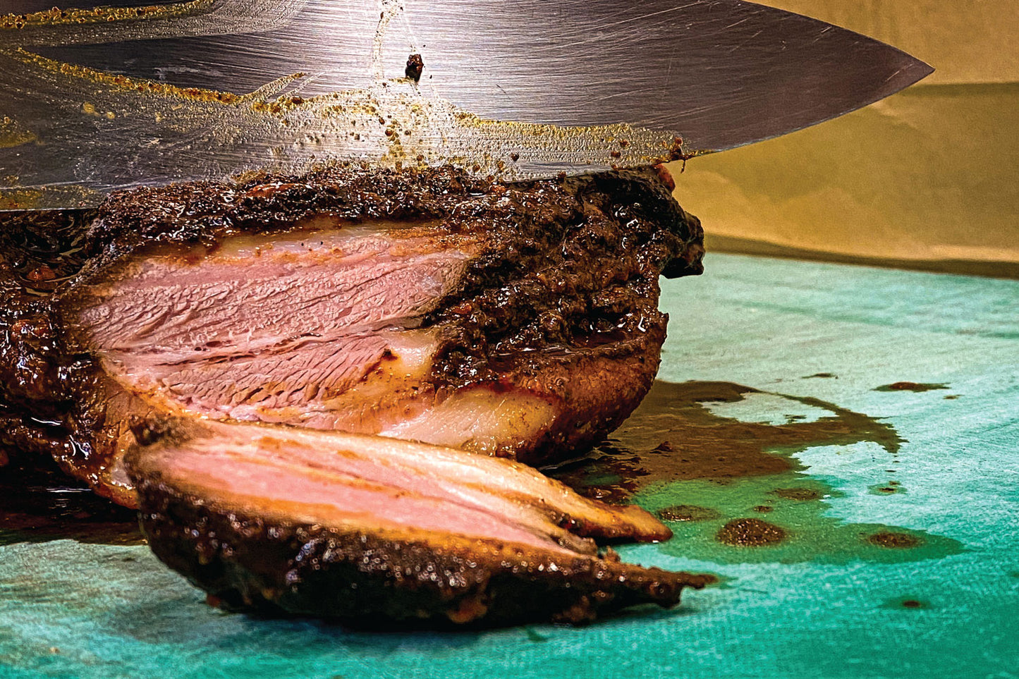 A knife cutting into a cooked slab of meat