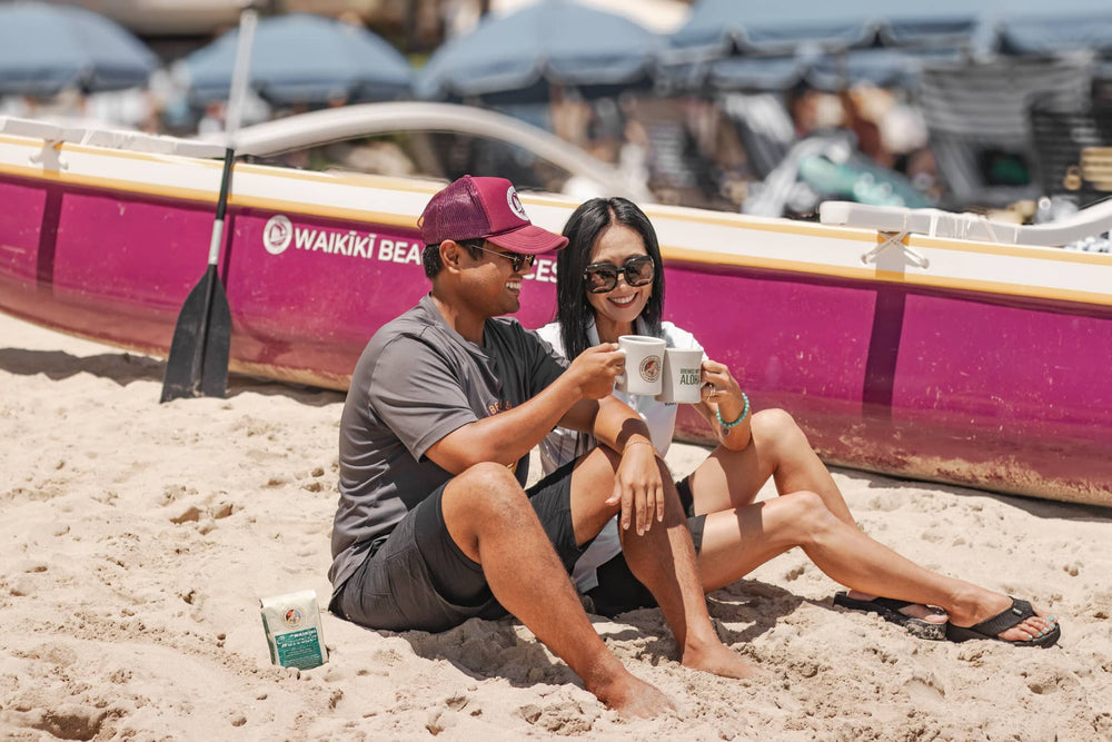 Two people enjoying a cup of Waikiki Waverider coffee at the beach