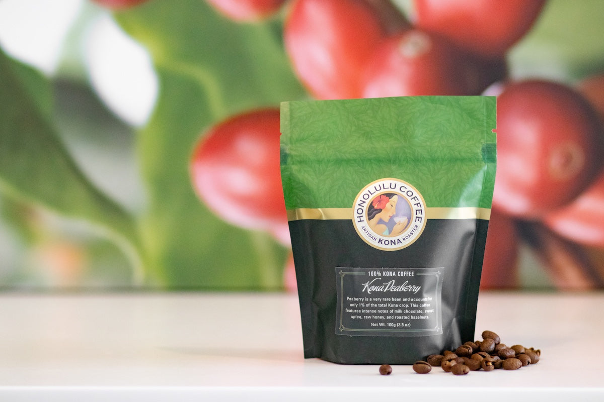 100 gram bag of Pure Kona Peaberry coffee with a coffee cherry backdrop