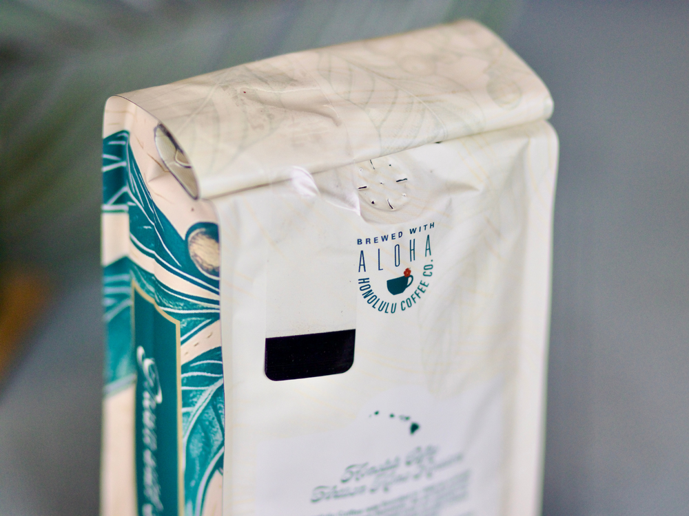 
                  
                    Details of the new Cherry Wave blend. "Brewed with Aloha" and "Honolulu Coffee Co." printed on the back of the bag.
                  
                
