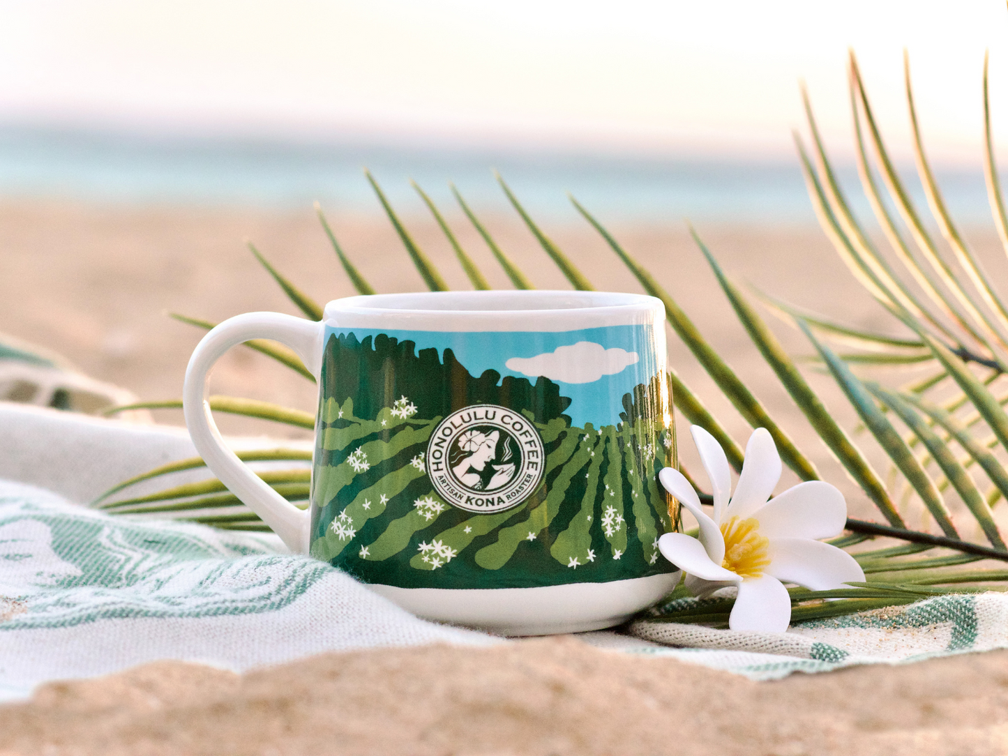 
                  
                    A mug with a flower on a beach towel.
                  
                