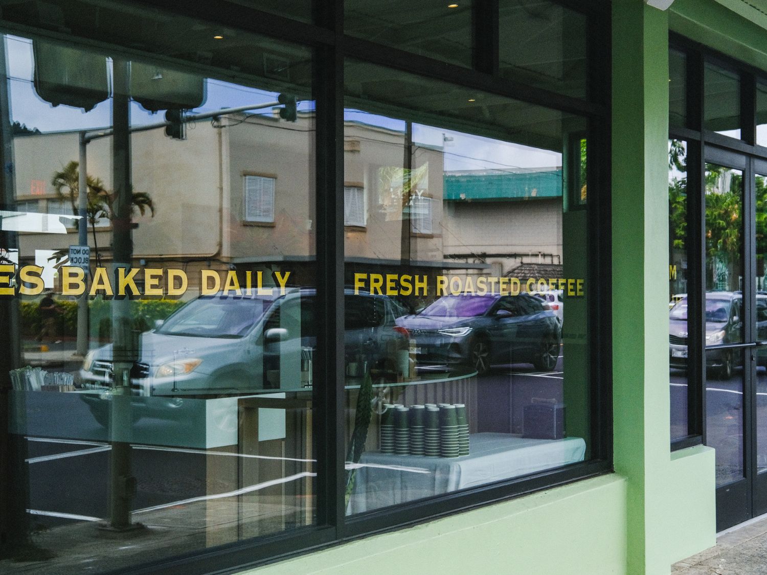 Storefront with glass windows displaying 'Baked Daily' and 'Fresh Roasted Coffee' signs.