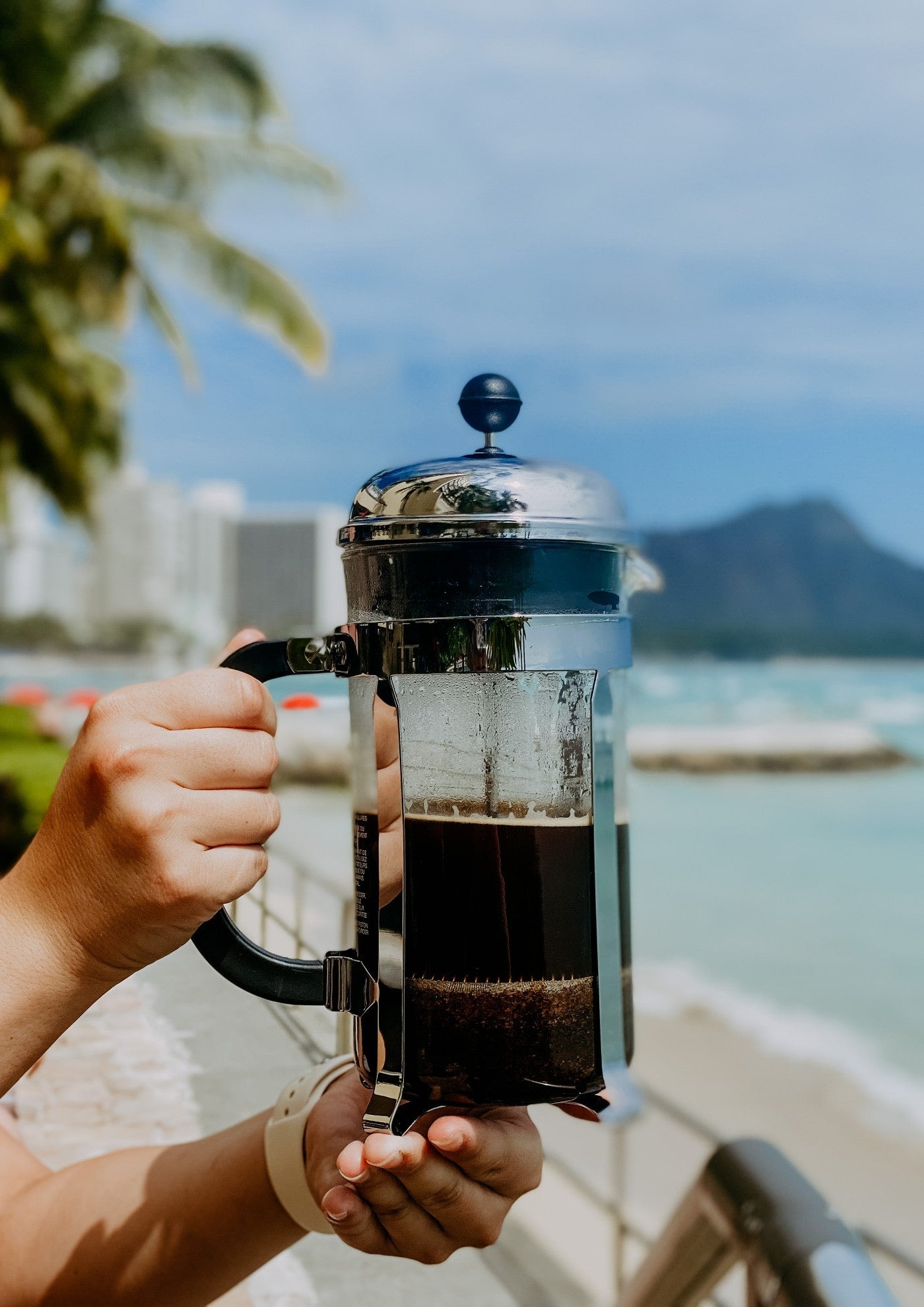 A French Press coffee maker in front of Diamond Head