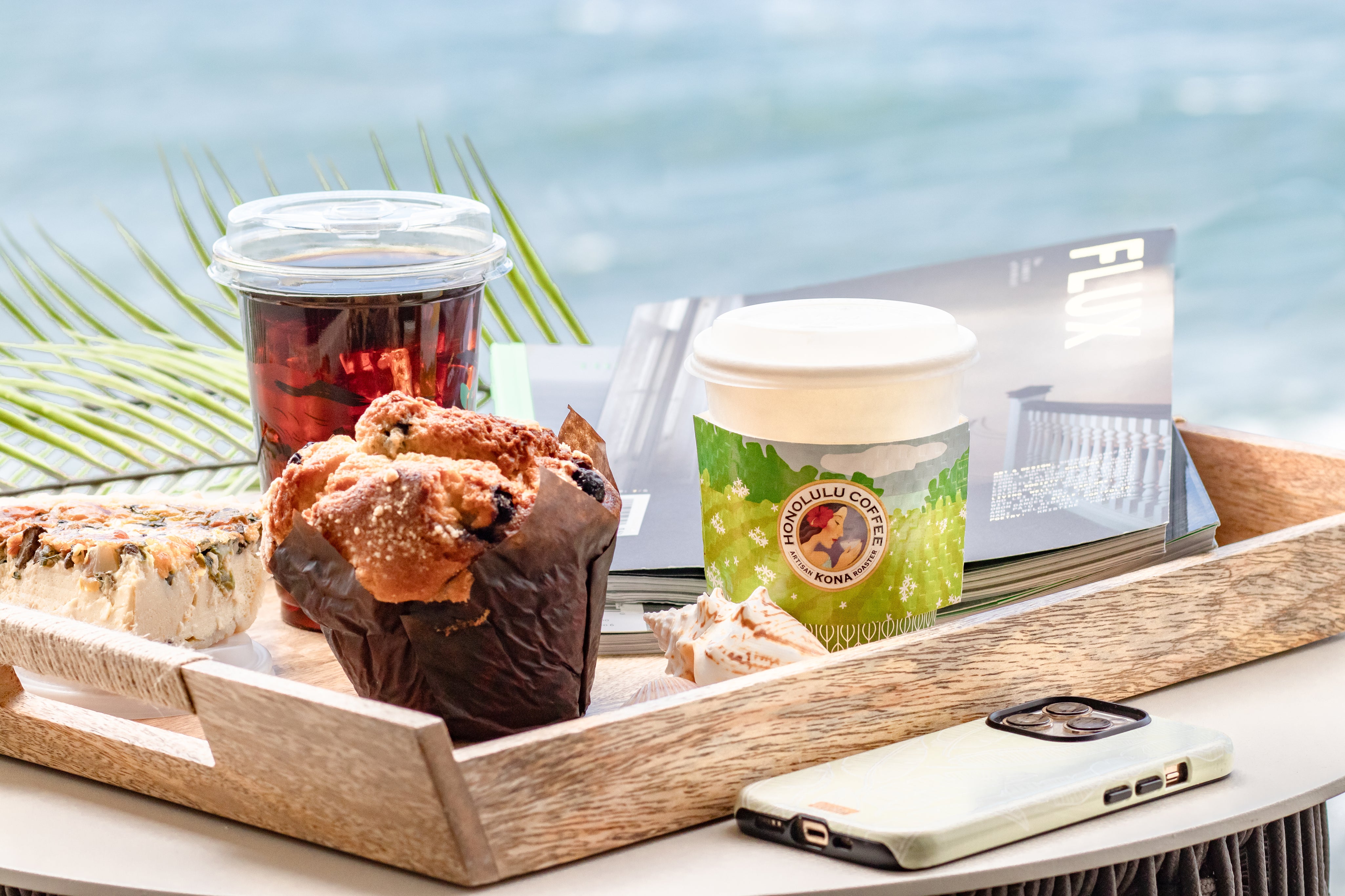 Tray with pastries, a cup of tea, and a smartphone on a table with a scenic background