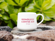 White mug with 'Honolulu Coffee Co' text on a natural background