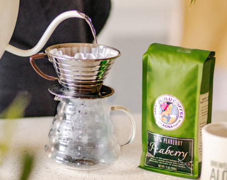 Coffee brewing setup with a green coffee bag labeled 'Peaberry' on a white surface.