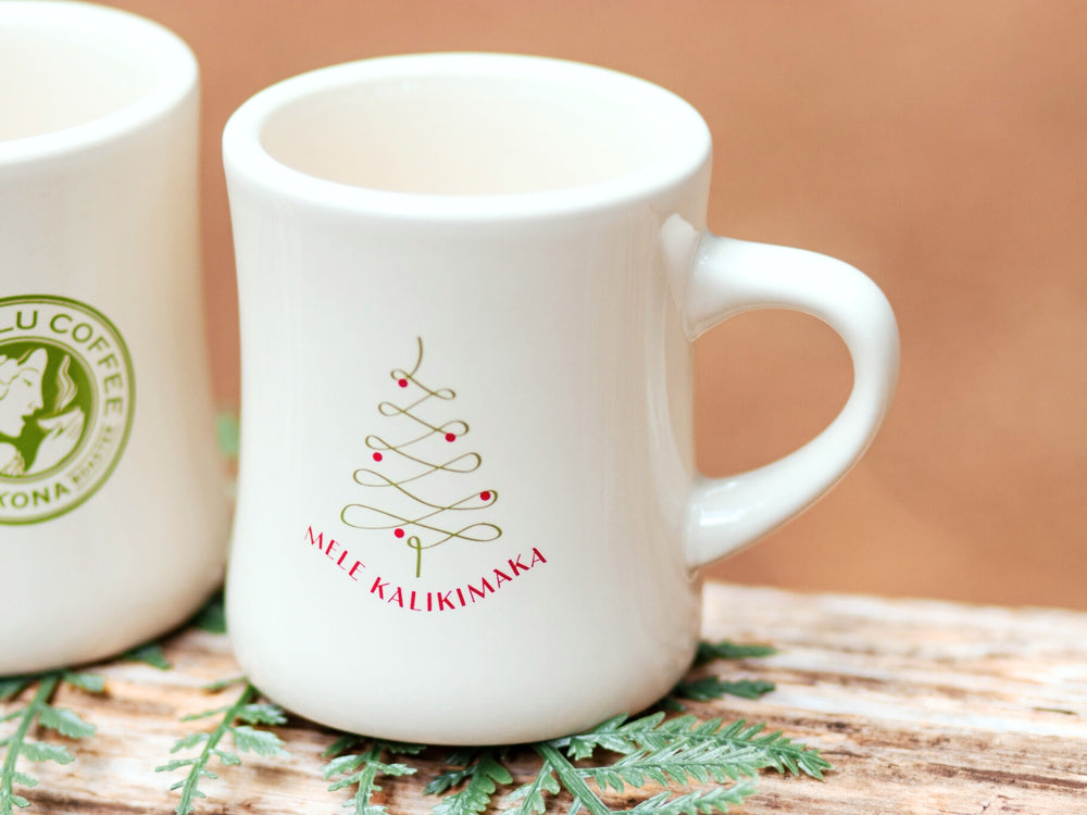 Two white mugs with Christmas-themed designs on a wooden surface.