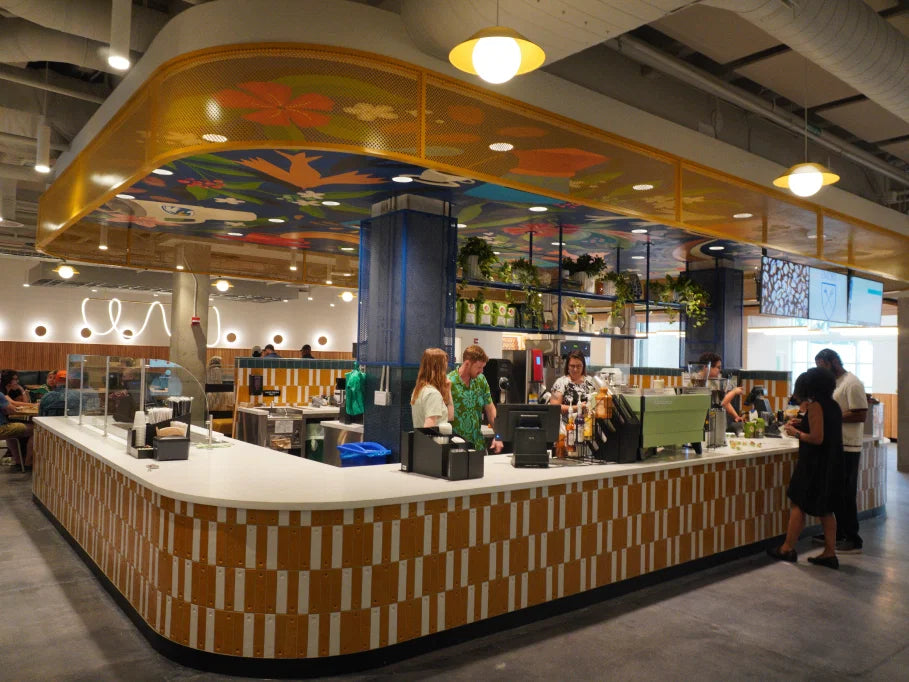 Modern cafeteria with a colorful ceiling and people at the counter