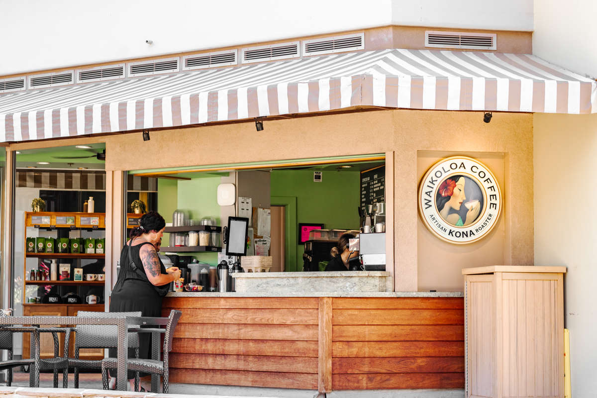 Waikoloa Coffee Kona coffee shop with striped awning and counter.