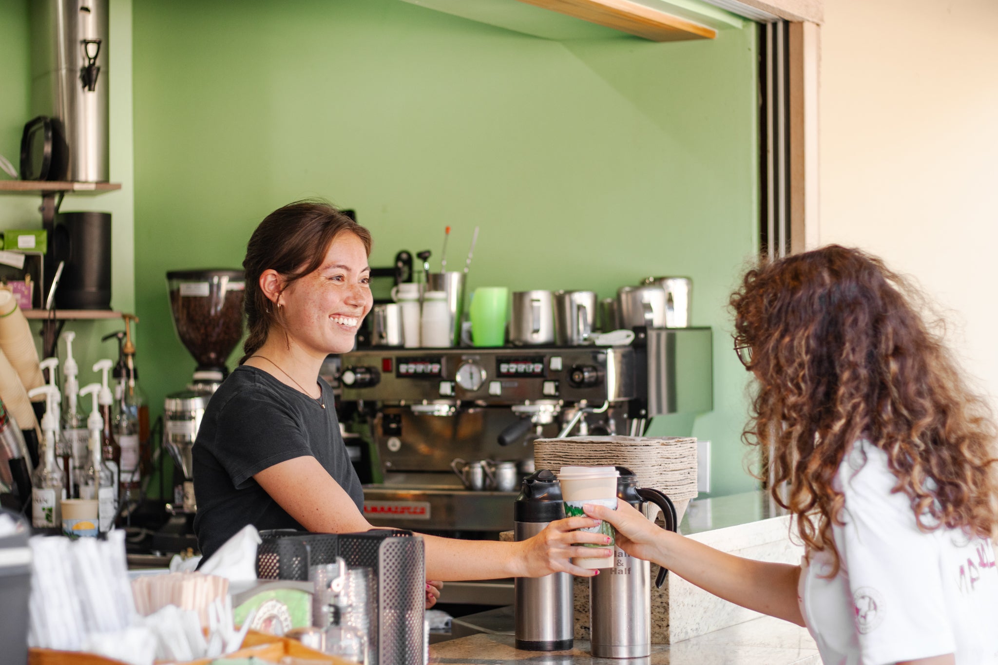 barista handing over a coffee beverage